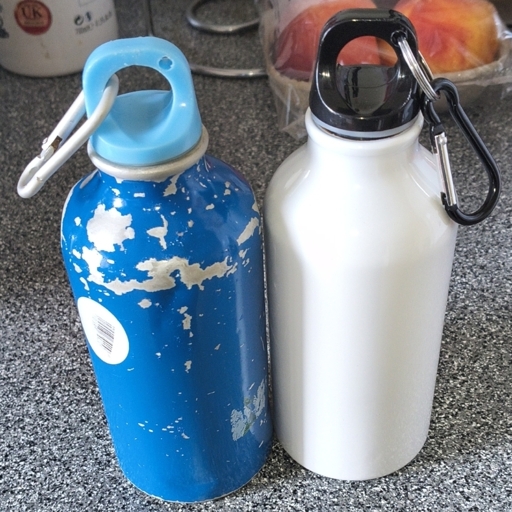 A beat up blue water bottle. Next to a new one in white